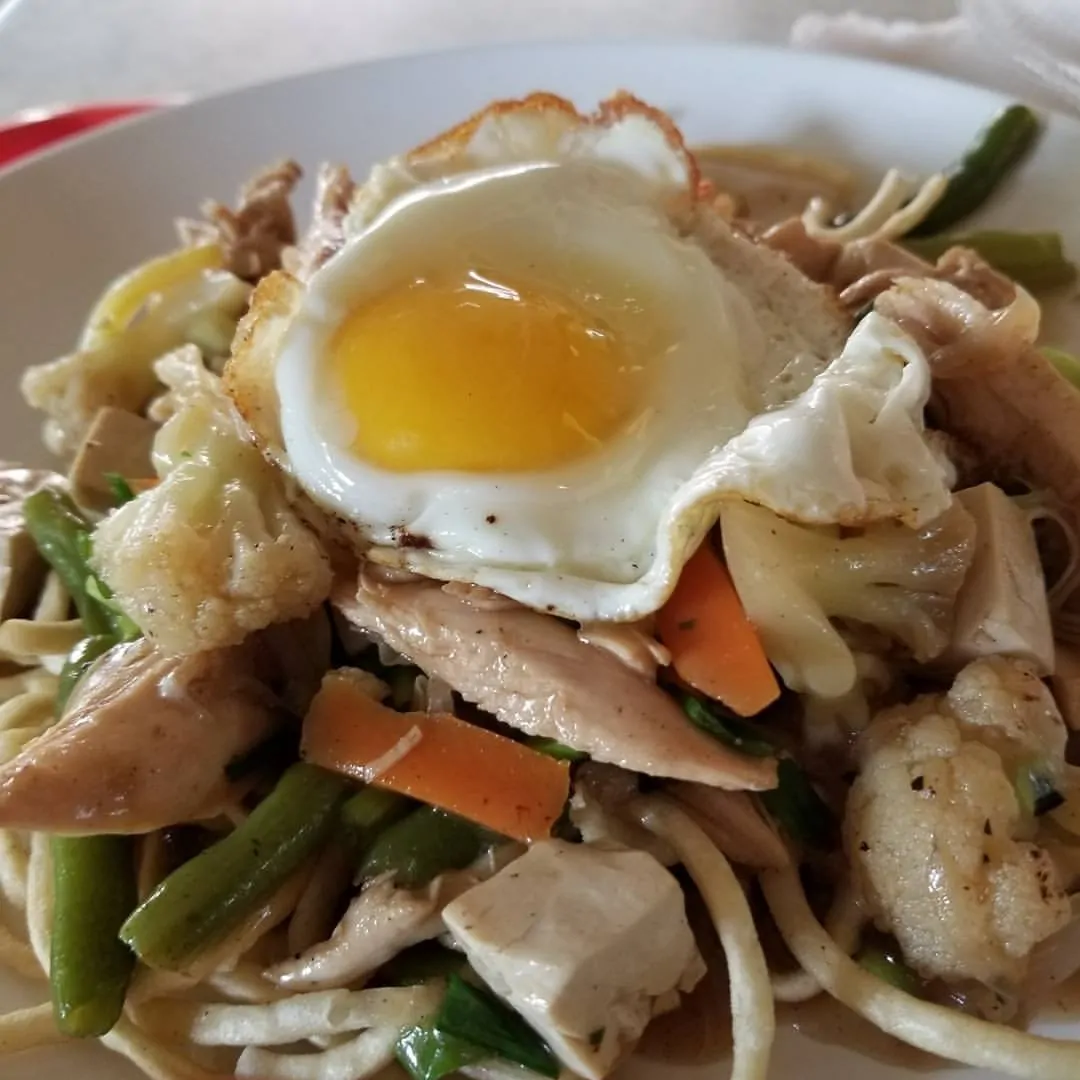 Volunteer Tourism bowl with chicken, noodles, and topped with fried egg