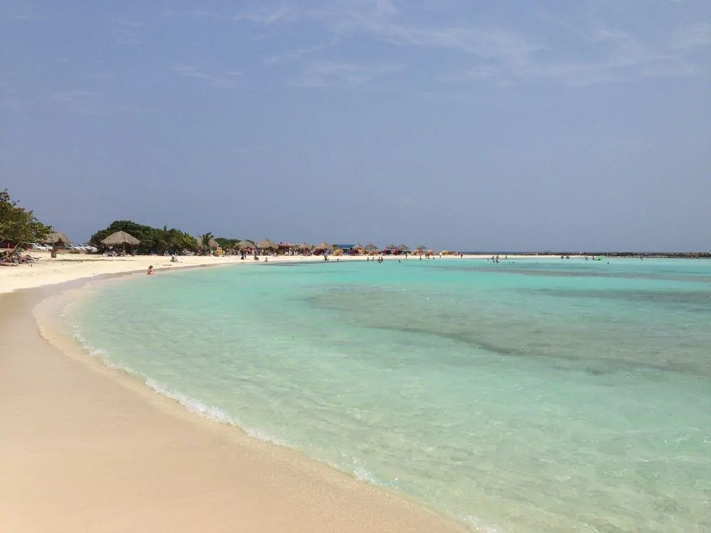 Aruba Sightseeing tips featured by top travel blog, The Common Traveler: beach in Aruba with boat in background
