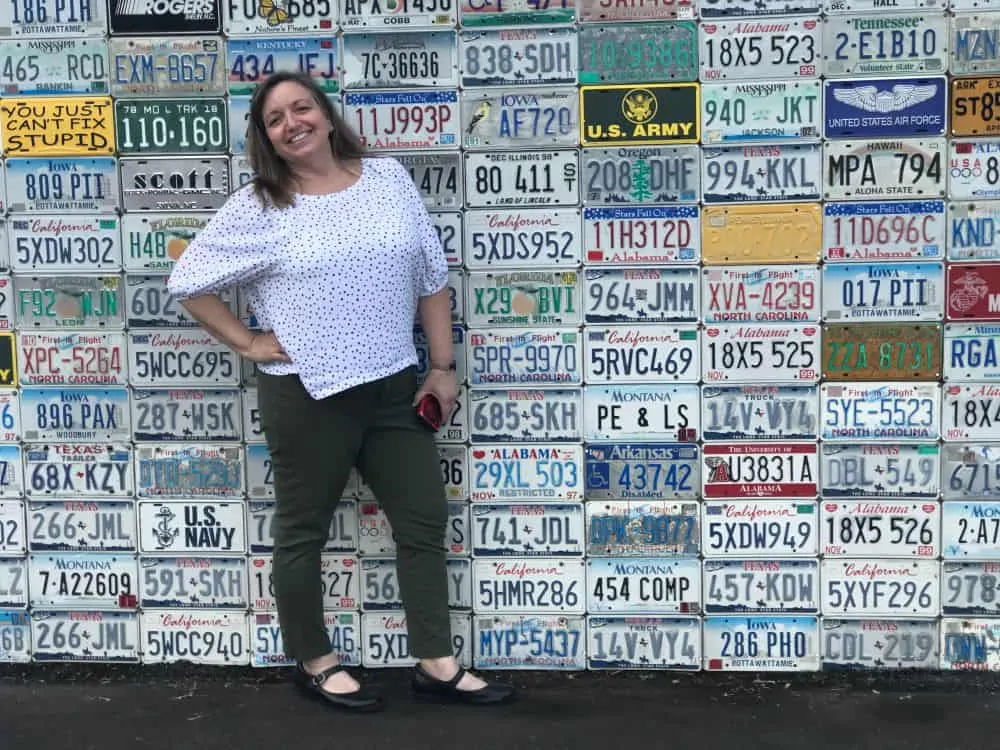 woman in front of wall license plates on building in Sylva, NC