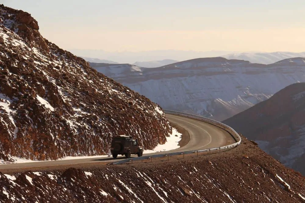 THE ULTIMATE ITINERARY FOR AN UNFORGETTABLE MOROCCO ROAD TRIP featured by top international travel blogger, The Common Traveler; overland truck on mountain roads in Morocco
