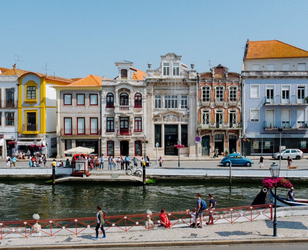 image: people by river in Aveiro, Portugal |Things to do in Portugal by popular US international blog, The Common Traveler: image of people walking by the water in front of some colorful building in Aveiro. 
