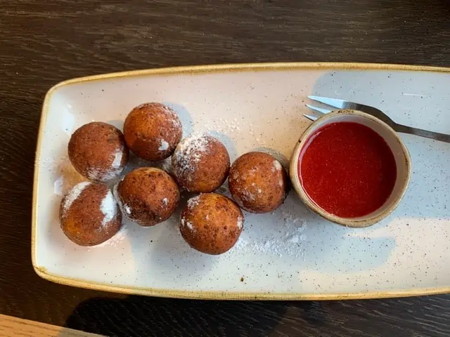 20 Lithuanian Food and Drinks to Try featured by The Common Traveler | image: donut balls with red sauce