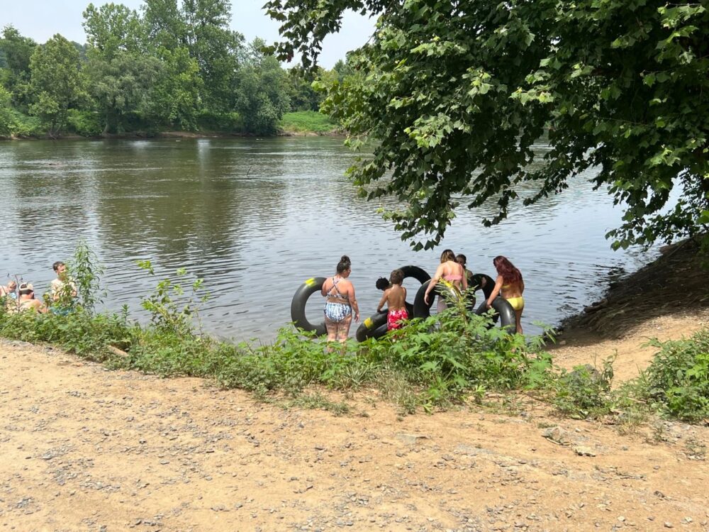 people on shore holding tubes to float