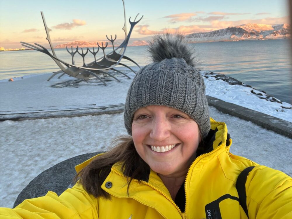 Know Before Visiting Iceland in Winter | The Common Traveler | image: woman in yellow jacket in front of Sun Voyager sculpture in Reykjavik