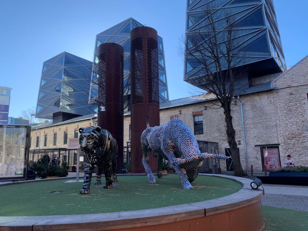 Best Things to do in Tallinn | The Common Traveler | image: metal sculpture in Rotermanni Tallinn with old buildings topped by glass buildings