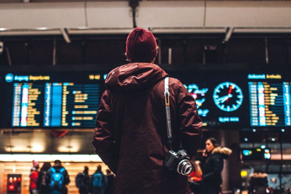 The Common Traveler | How Your Credit Affects Your Travel | image: man with camera looking at departures and arrival board