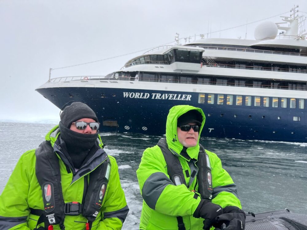 What to Pack for an Antarctica Cruise | The Common Traveler | image: two men in lime jackets with Atlan Ocean Voyages World Traveller ship in background