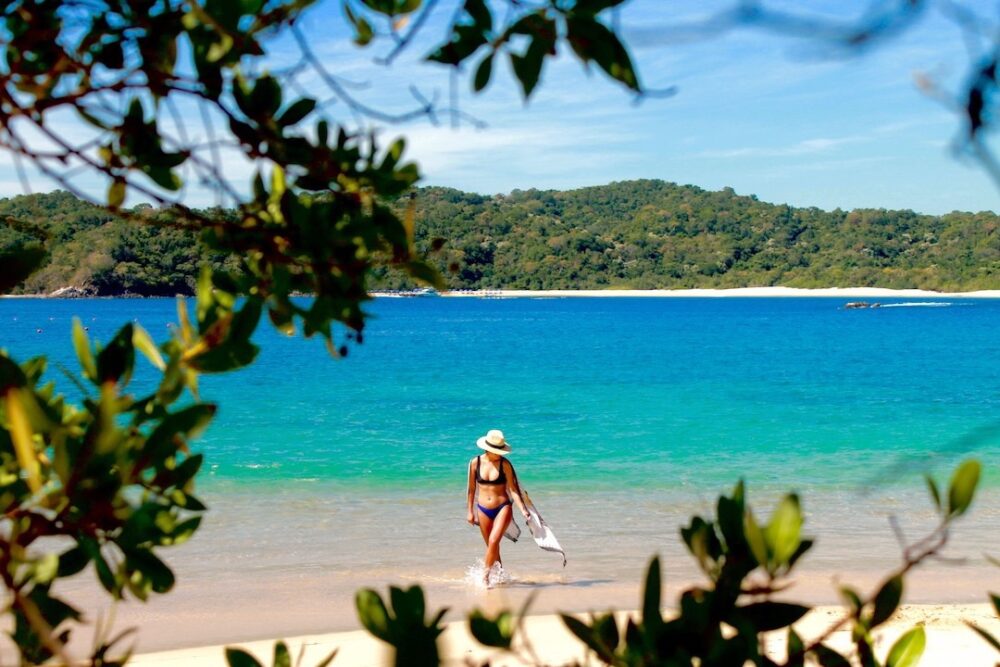 Things to Do in Oaxaca Mexico | The Common Traveler | image: woman in hat walking along shore in Hualtuco