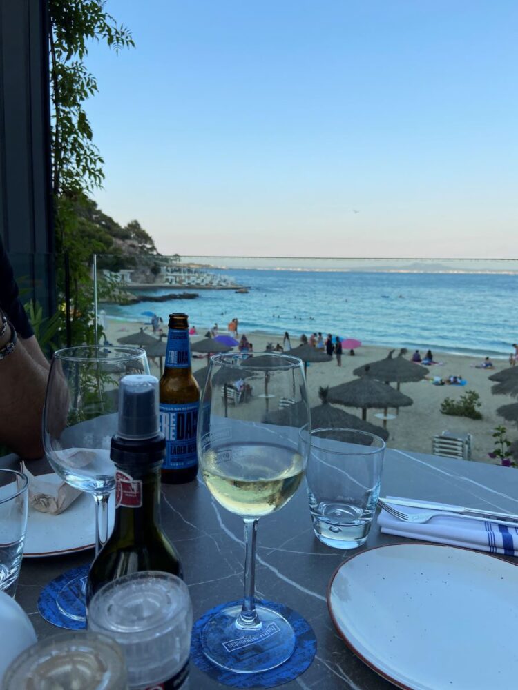 Best Things to Do in Mallorca Spain | The Common Traveler | image: restaurant table with wine and beer at beach