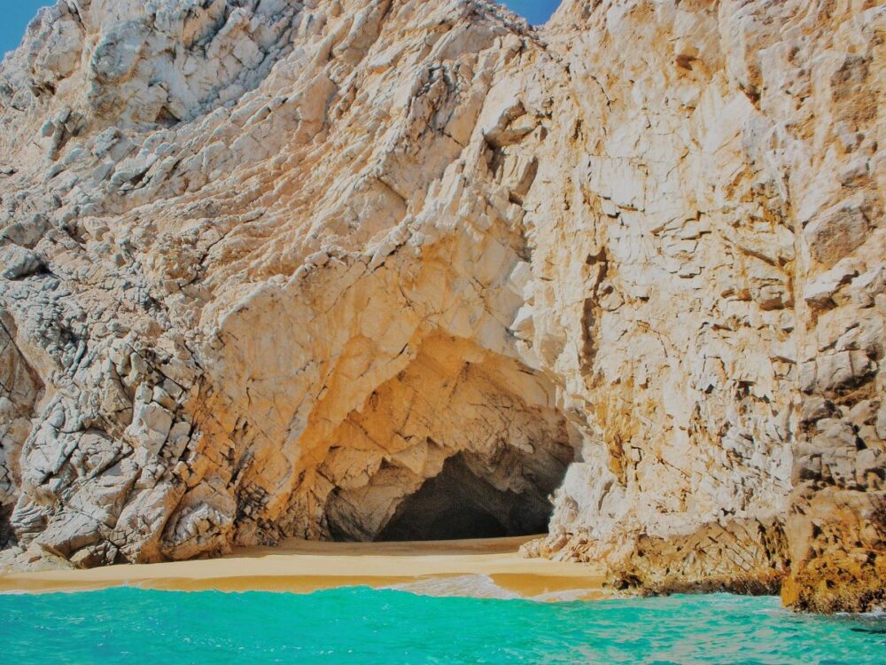 Cabo vs Cancun: Where Should You Go? | The Common Traveler | image: beach with cave in Cabo