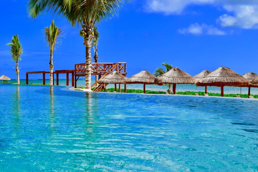 Cabo vs Cancun: Where Should You Go? | The Common Traveler | image: pool and palepas on beach in Cancun