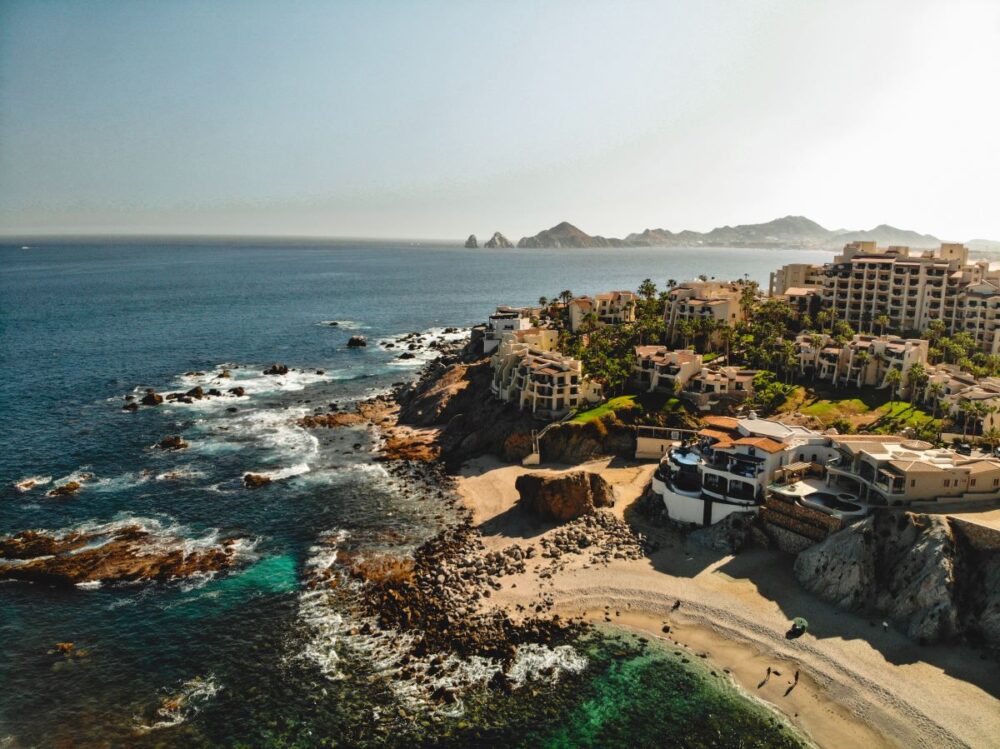 Cabo vs Cancun: Where Should You Go? | The Common Traveler | image: buildings on rocky outcrop in Cabo