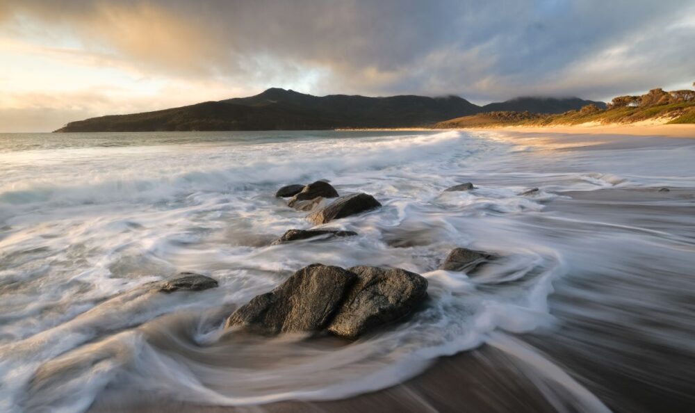 5 Amazing Beaches to Visit in Australia | The Common Traveler | image: rocks and waves at Wineglass Bay
