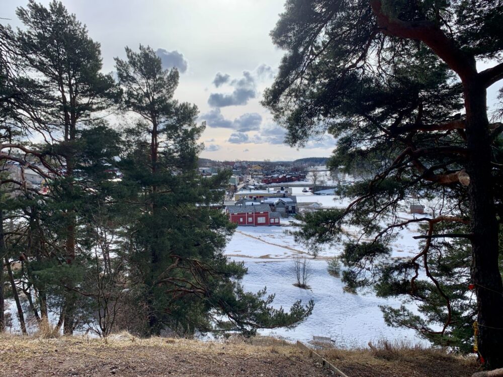 Porvoo Day Trip From Helsinki | The Common Traveler | image: view of Porvoo through trees from hill across river