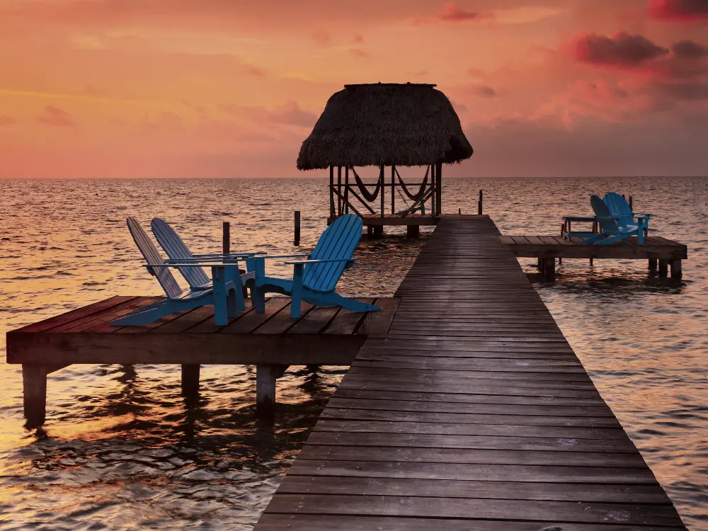 Caye Caulker or Ambergris Caye? | The Common Traveler | image: wood chairs on deck at sunset in Ambergris Caye