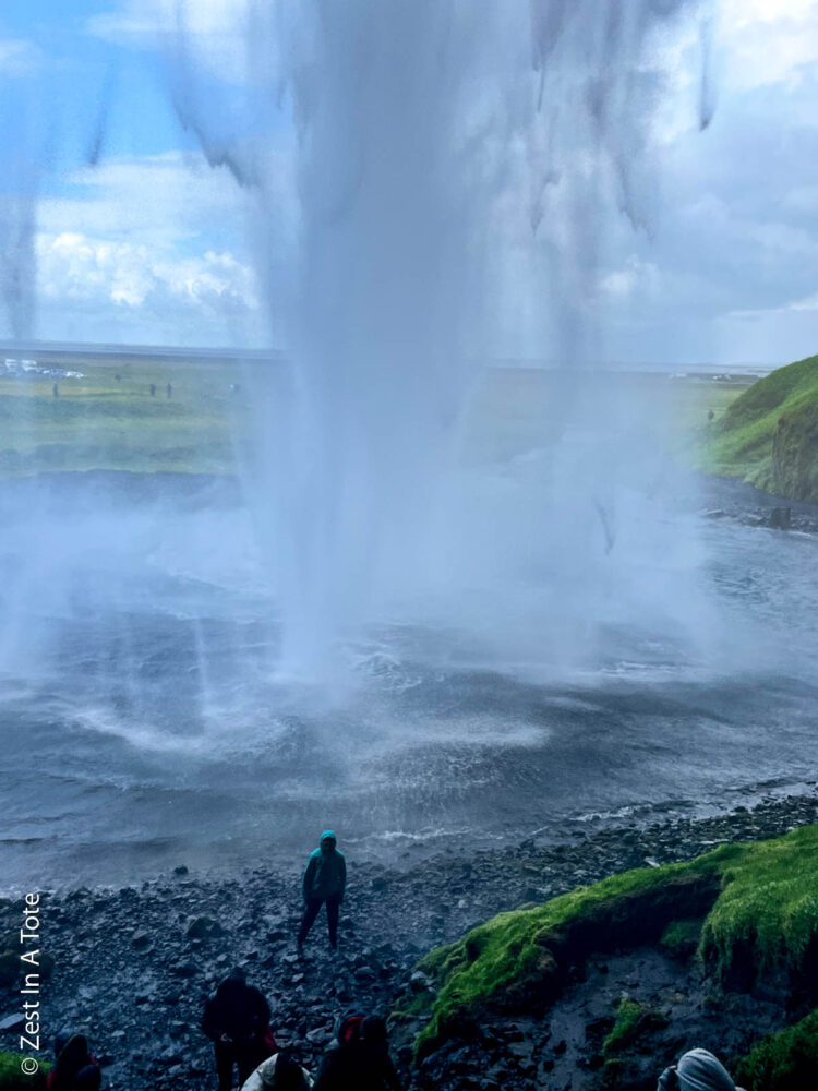 Best Things to Do in Vik, Iceland | The Common Traveler | image: woman standing behind Seljalandsfoss waterfall