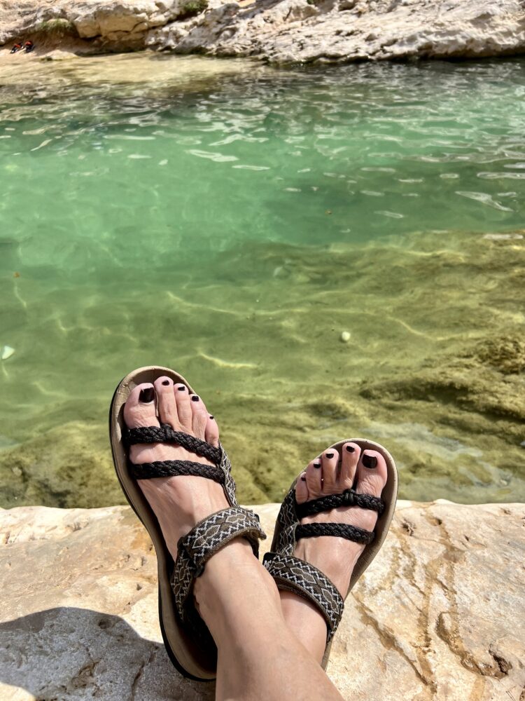 Middle East Packing List for Women | The Common Traveler | image: sandals on feet in Wadi Shab, Oman