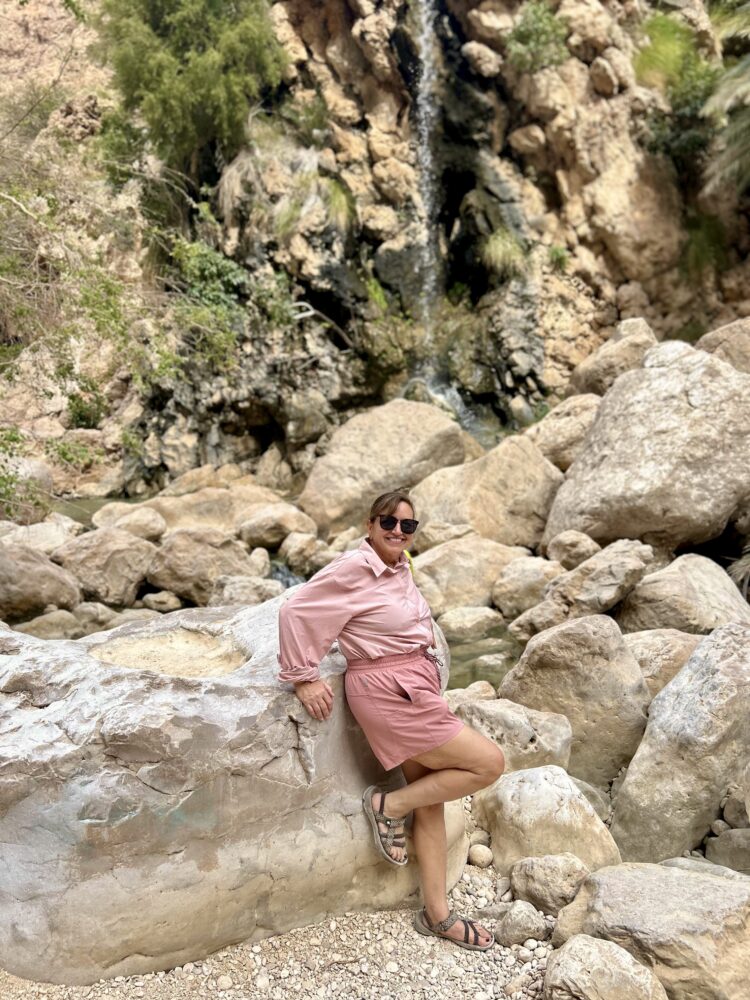 Middle East Packing List for Women | The Common Traveler | image: woman in pink shorts and pink long sleeve shirt in front of waterfall
