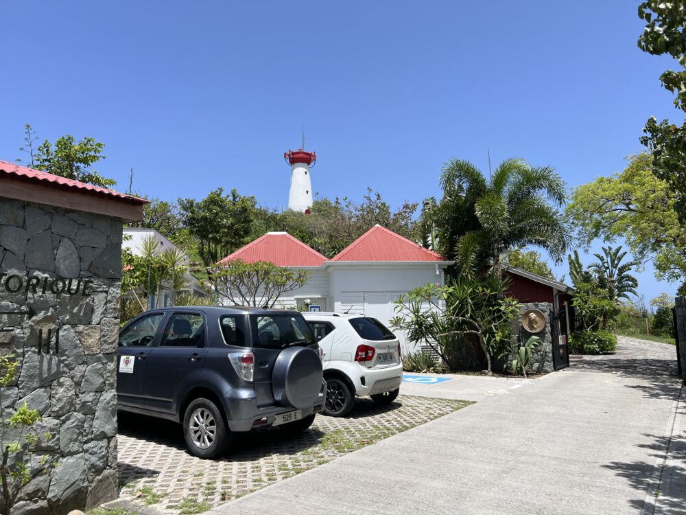 Self-Guided Walking Tour of Gustavia, St Barts | The Common Traveler | image: white lighthouse with red top with cars in parking in forefront