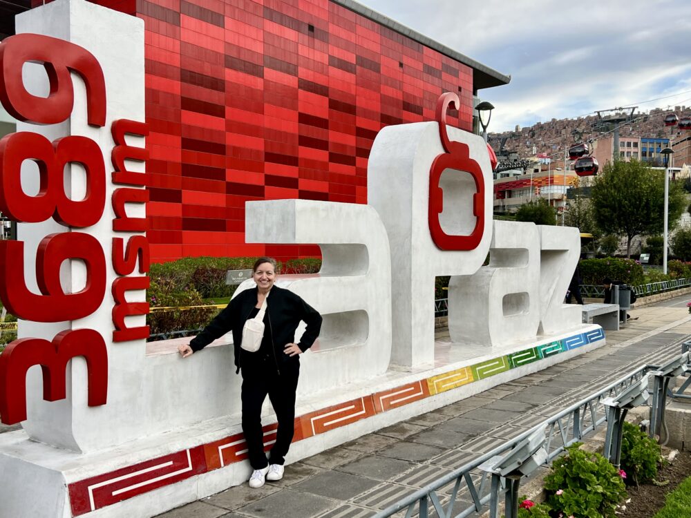 Guide to La Paz, Bolivia | The Common Traveler | image: La Paz altitude sign with woman in black in front
