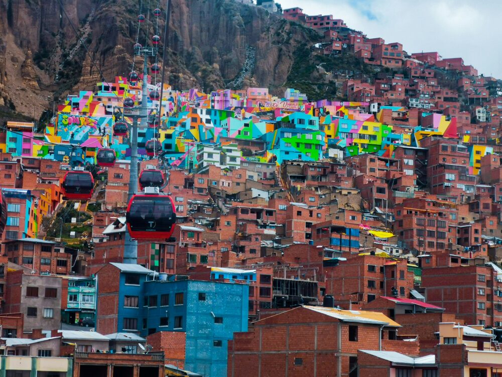 Guide to La Paz, Bolivia | The Common Traveler | image: colorful buildings and unpainted buildings with red cable cars