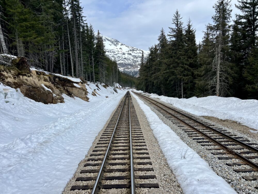 Best Scenic Steam Train Rides in America | The Common Traveler | image: train tracks in the snow with pine trees and snow covered mountains