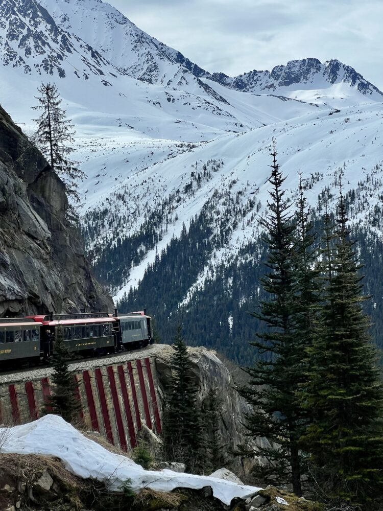 Best Scenic Steam Train Rides in America | The Common Traveler | image: train going around a curve with snow covered peaks and pine trees