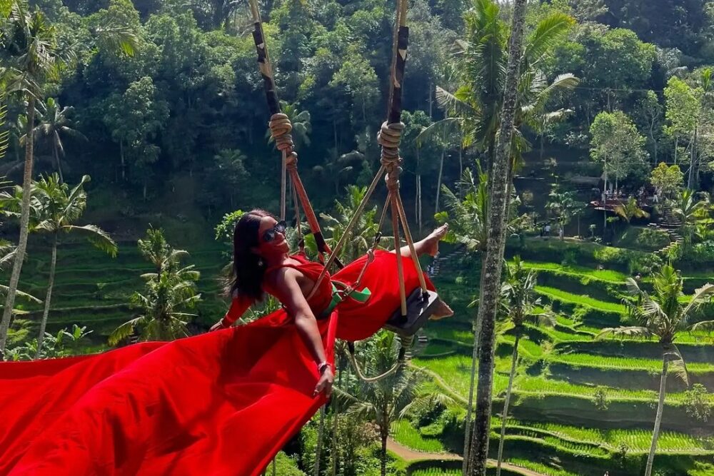 Luxury Bali on a Backpacker's Budget | The Common Traveler | image: woman in red dress on swing with green rice terraces in background
