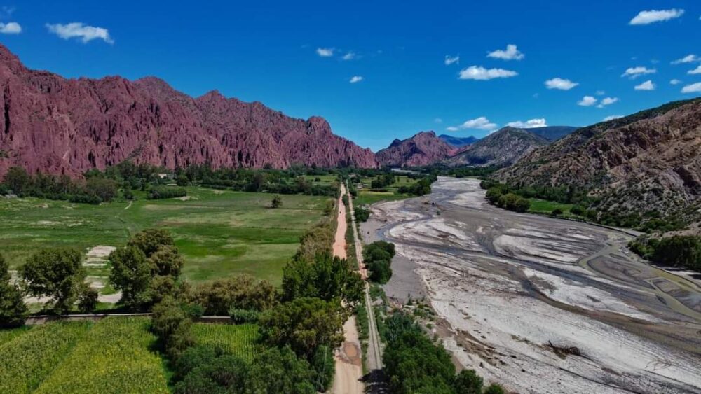 Gringo Trail in Bolivia: 5 Places to Escape the Usual Tourist Route | The Common Traveler | image: red rocks, green fields, and dry river bed of Tupiza, Bolivia